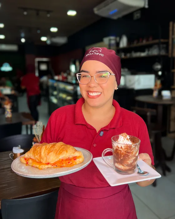 Atendente da Serra Minas servindo croissant e bebida